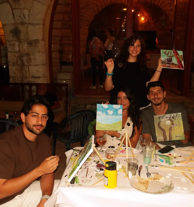 A table of guests under a stone arch, canvases raised
