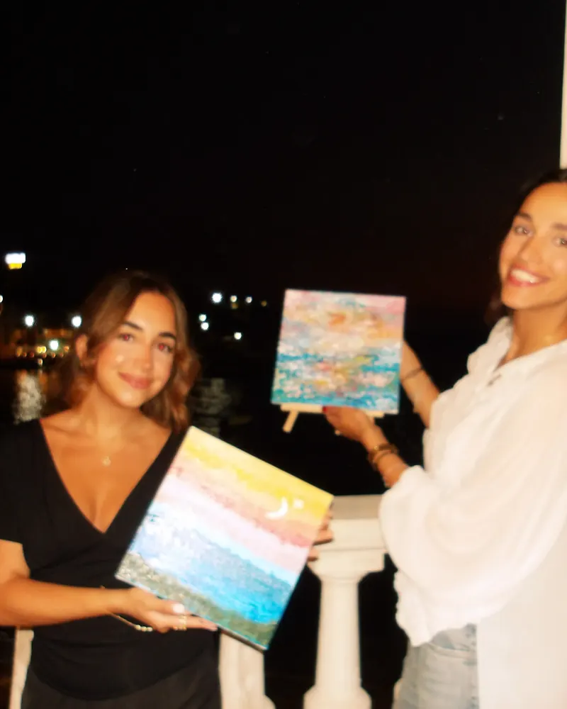 A finished canvas held up against the lights of the bay