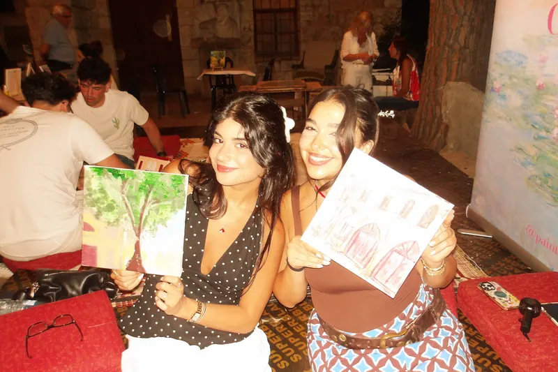 Two guests holding up the canvases they painted, still wet