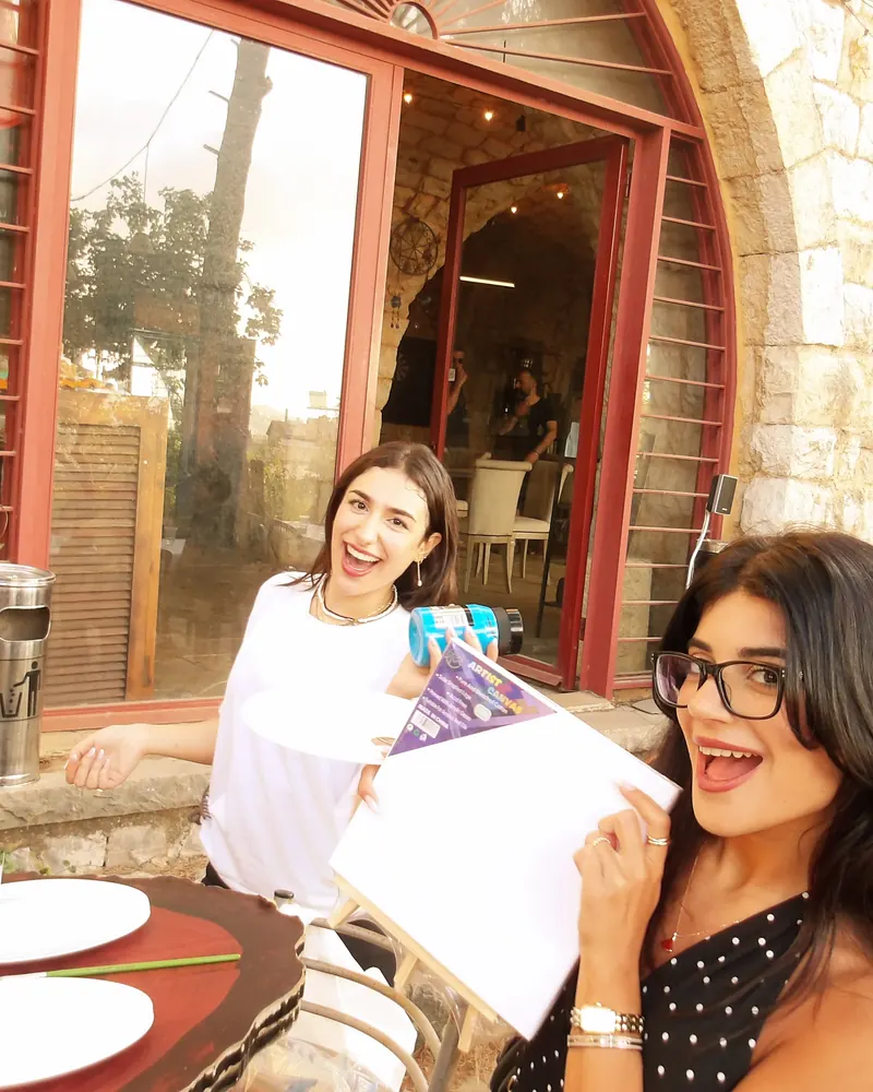 Two guests laughing with their finished canvases in a stone doorway