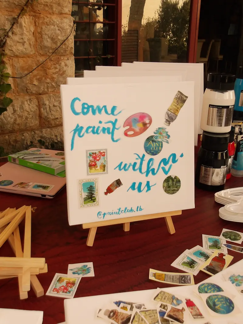 The supply table: easels, brushes and a hand-painted Come paint with us sign