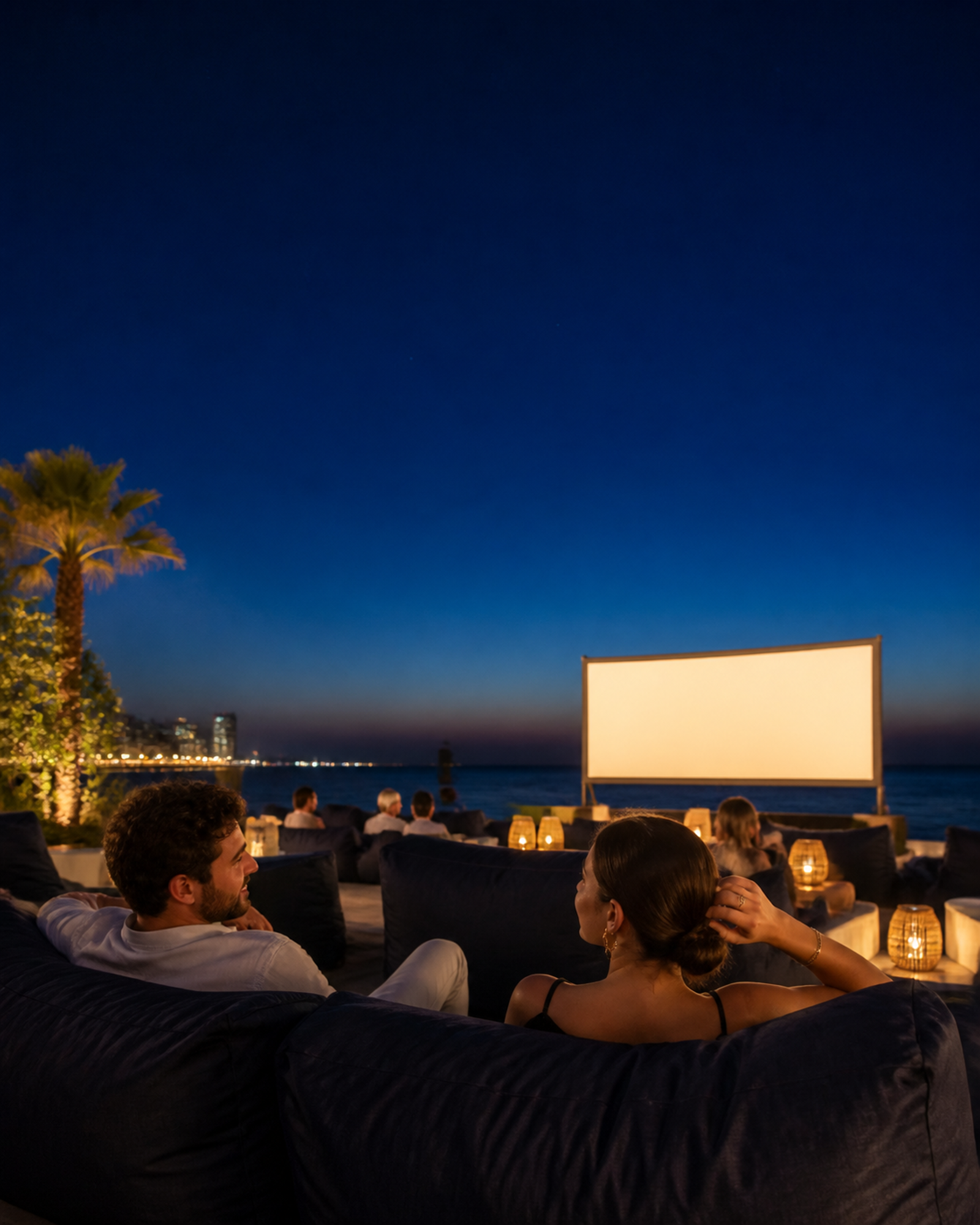 Two adults relaxing in outdoor cinema seating beside the Beirut waterfront.